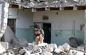 A boy sits at the site of an air strike at a residential area near Sanaa Airport